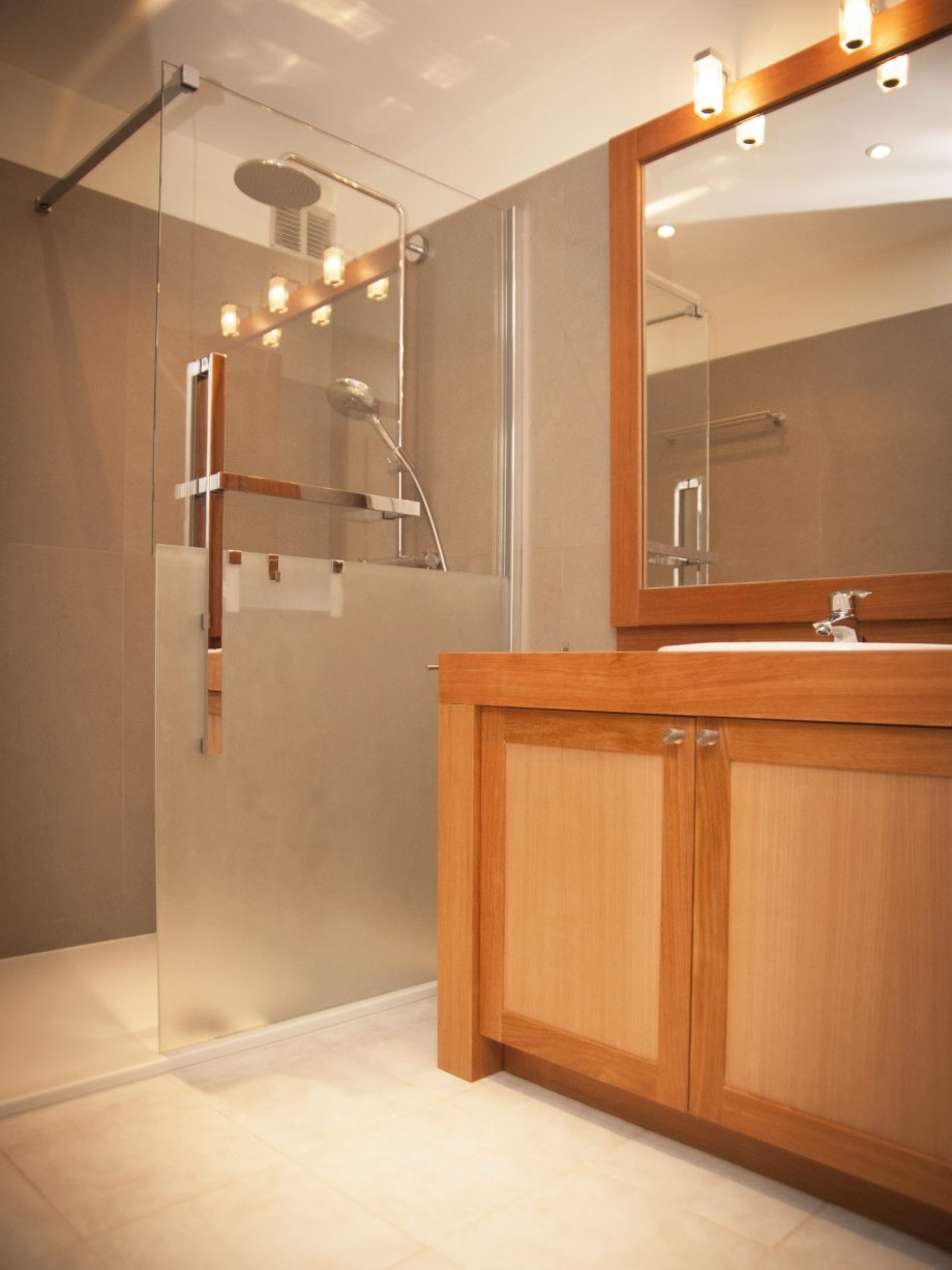 Salle de bain lumineuse avec des meubles et un cadre miroir en afzelia